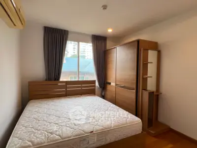 Cozy bedroom with large window and wooden furniture, perfect for relaxation.