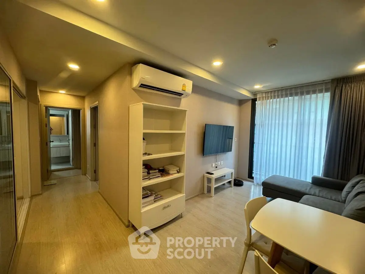 Modern living room with cozy seating and natural light, featuring a sleek air conditioning unit and stylish decor.