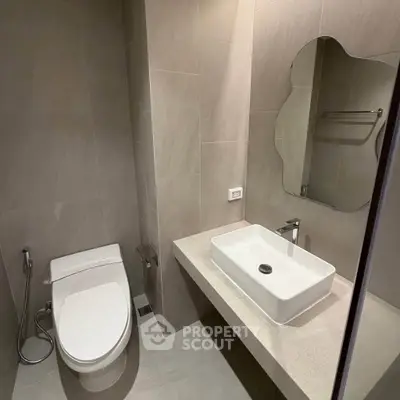 Modern bathroom with sleek fixtures and contemporary design, featuring a stylish sink and toilet.