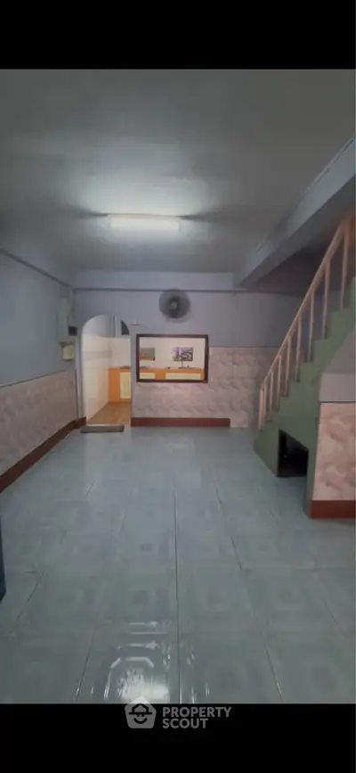 Spacious living room with tiled flooring and staircase, ideal for family gatherings.