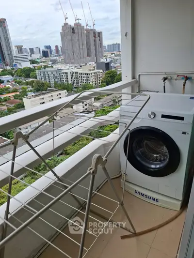High-rise balcony with washing machine and cityscape view, perfect for urban living.