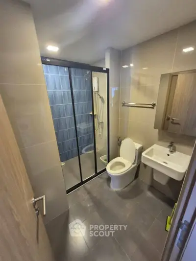 Modern bathroom with sleek design and glass shower enclosure in a contemporary apartment.