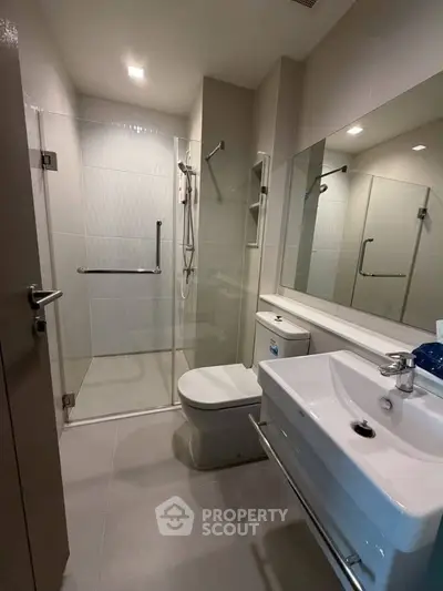 Modern bathroom with glass shower, sleek fixtures, and elegant tile design.