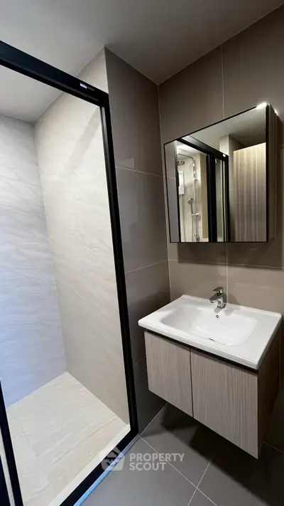 Modern bathroom with sleek vanity and spacious shower area in contemporary design.