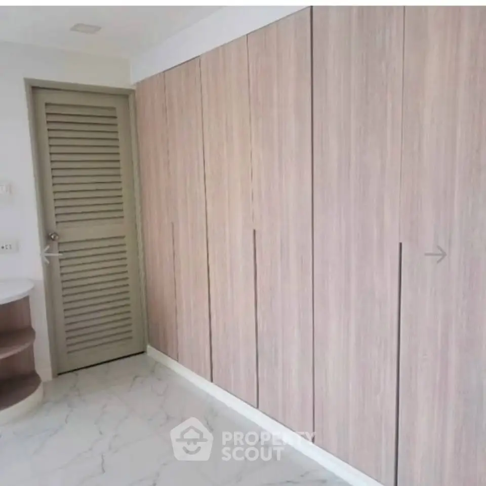 Spacious modern storage area with sleek wooden cabinets and elegant marble flooring.