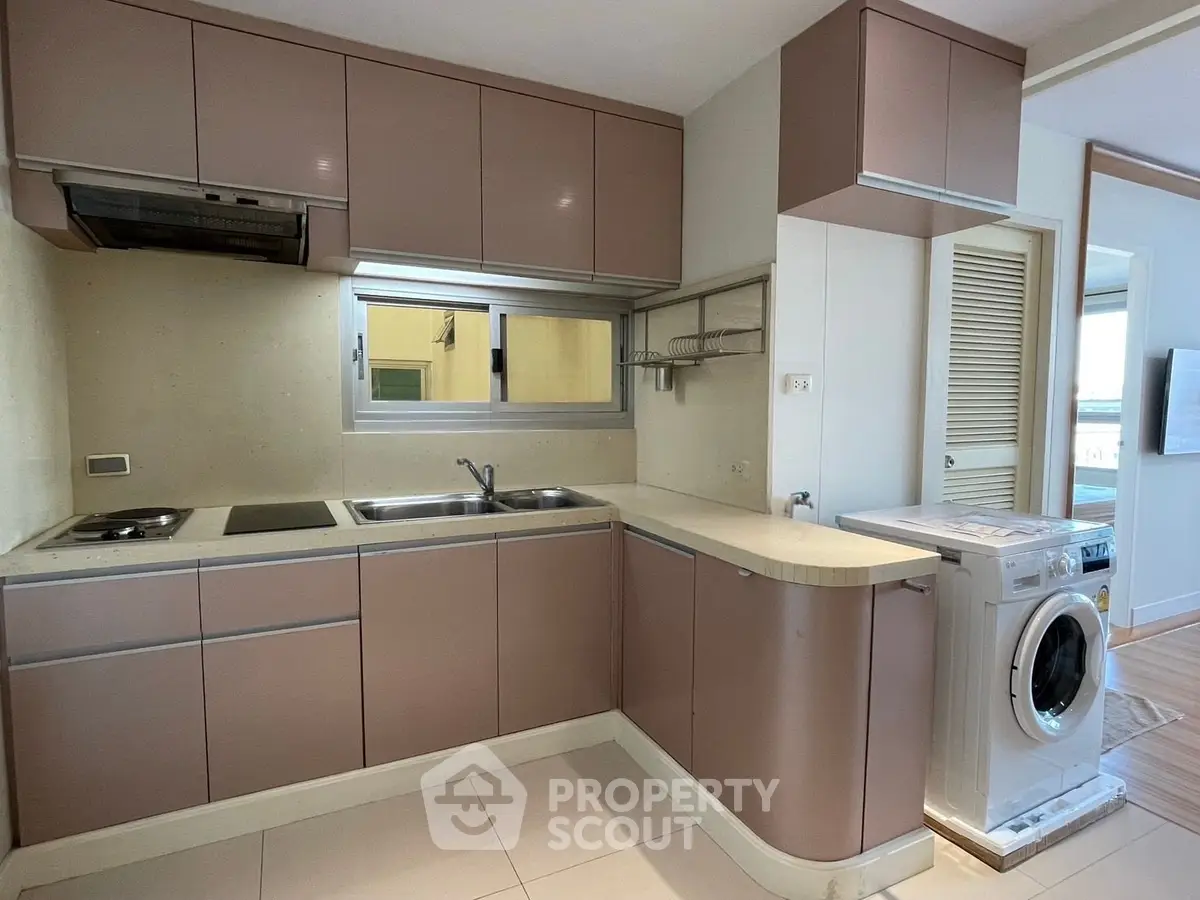 Modern kitchen with sleek cabinetry and built-in washing machine in a stylish apartment.