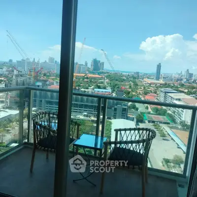 Stunning city view from high-rise balcony with cozy seating area.