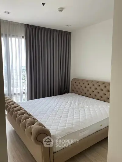 Elegant bedroom with plush bed and floor-to-ceiling window offering city views.