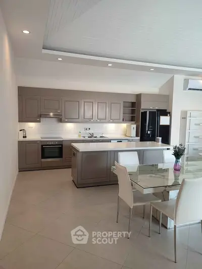 Modern kitchen with sleek cabinetry and dining area, featuring open layout and contemporary design.