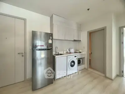 Modern kitchen with sleek appliances and washing machine in compact layout