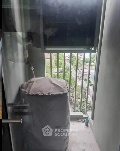 Compact balcony with washing machine and city view, ideal for urban living.