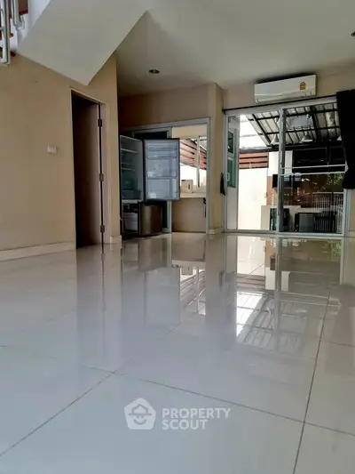 Spacious modern interior with glossy tile flooring and open fridge in a bright setting.