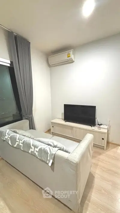 Modern living room with sleek sofa, TV, and air conditioning in a cozy apartment setting.