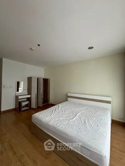 Spacious bedroom with wooden flooring and modern furniture