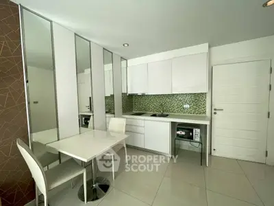 Modern kitchen with sleek white cabinets and mosaic backsplash in a stylish apartment.