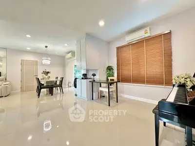 Spacious modern living room with dining area and piano, featuring sleek design and ample natural light.