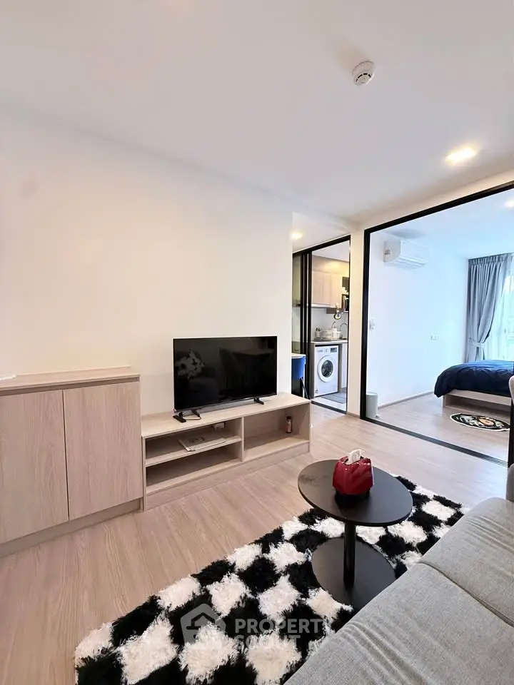 Modern living room with stylish decor and open view into bedroom, featuring sleek furniture and cozy ambiance.