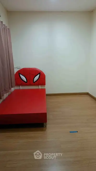 Minimalist bedroom with unique superhero-themed bed frame and wooden flooring.