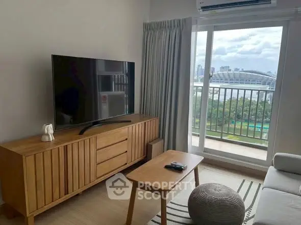 Modern living room with balcony view, featuring sleek furniture and a large TV, perfect for urban living.