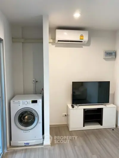 Modern living room with air conditioner, TV, and washing machine in a compact space.