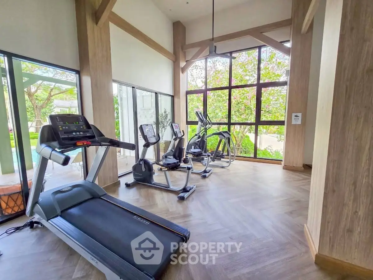 Modern gym with large windows and exercise equipment in a bright, airy space.