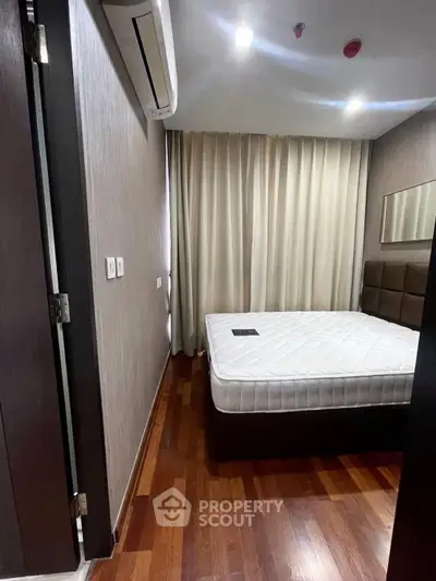 Modern bedroom with wooden flooring and air conditioning in a stylish apartment.