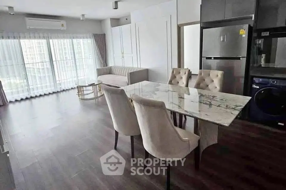 Spacious modern living room with elegant dining area and large windows in a stylish apartment.