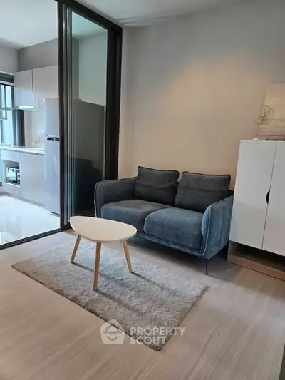 Modern living room with cozy sofa and sleek kitchen in open layout apartment.