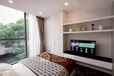 Modern bedroom with large window and built-in shelves, featuring a sleek TV setup.