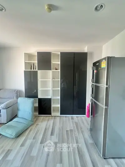 Modern living room with sleek storage and stainless steel fridge