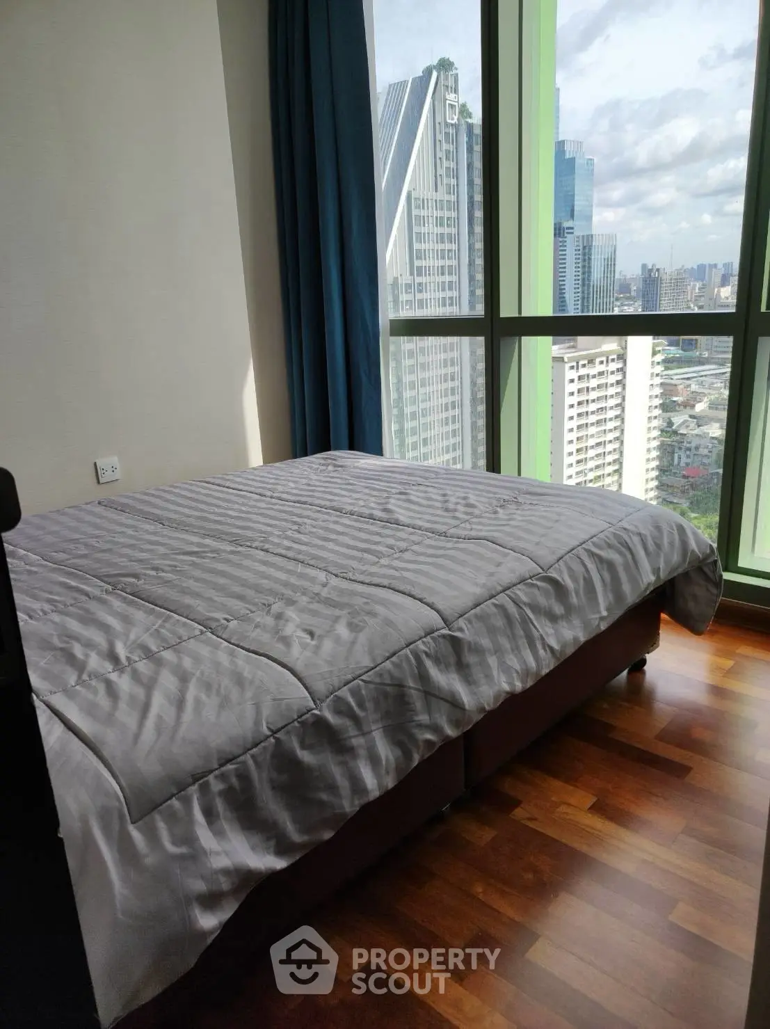 Modern bedroom with stunning city view and large windows in high-rise apartment.