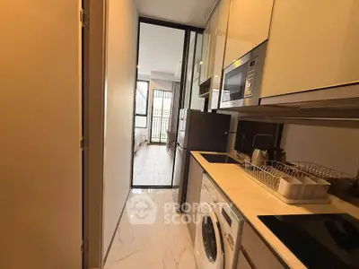 Modern kitchen with sleek appliances and open layout leading to bright living area.