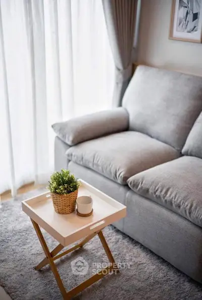 Cozy living room with plush gray sofa and stylish coffee table near large window.