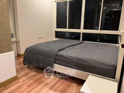 Modern bedroom with large windows and city view, featuring sleek wooden flooring and minimalist decor.