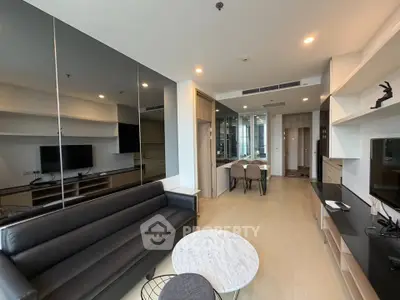 Modern living room with sleek black sofa and marble coffee table, open layout leading to dining area.