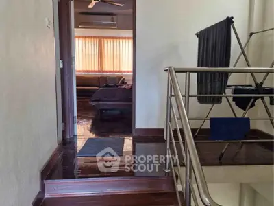 Spacious interior with wooden flooring and modern railing, leading to a cozy living area.