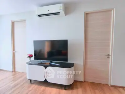 Modern living room with sleek TV stand and air conditioning, featuring minimalist design and wooden flooring.