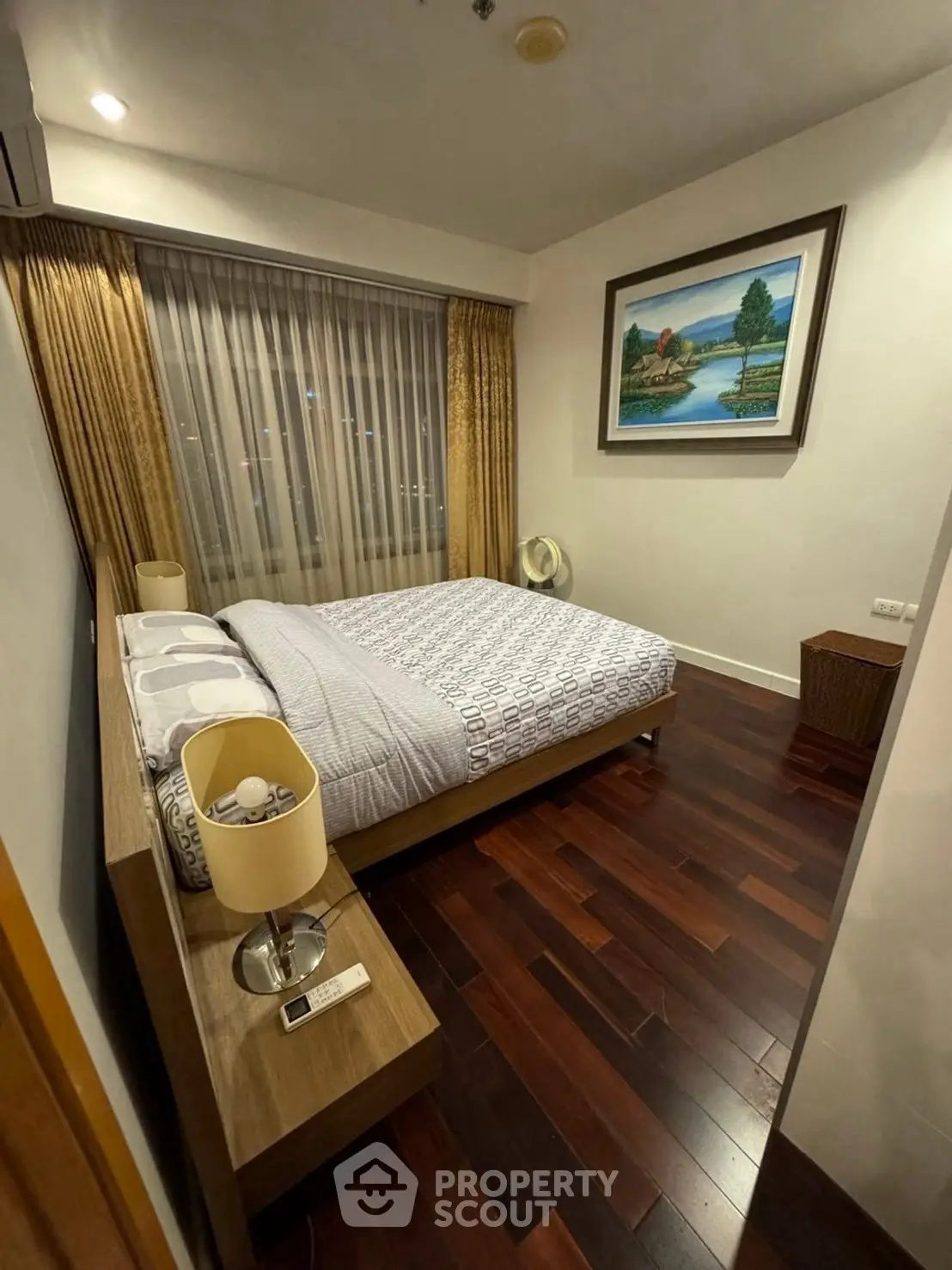 Cozy bedroom with wooden flooring and elegant decor in modern apartment.