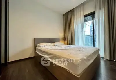 Spacious bedroom with modern decor and large windows offering natural light and city views.