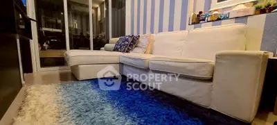 Cozy living room with plush white sofa and vibrant blue rug, perfect for relaxation.