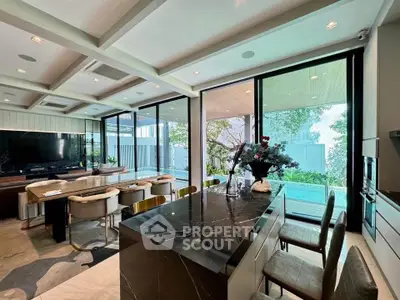 Luxurious open-plan living room with modern kitchen and pool view, perfect for entertaining.