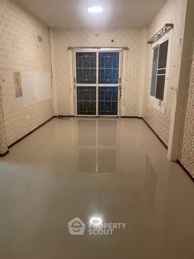 Spacious empty room with glossy tiled floor and large window, perfect for customization.