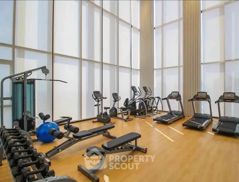 Spacious modern gym with state-of-the-art equipment and floor-to-ceiling windows.