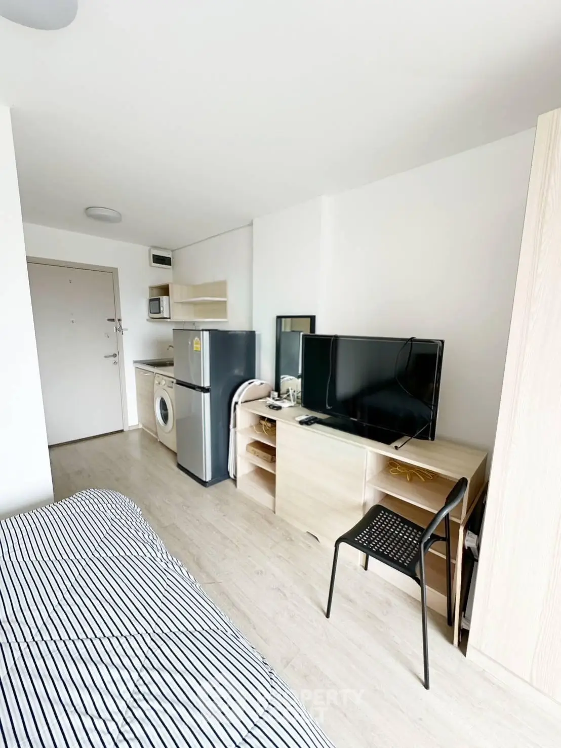 Modern studio apartment with compact kitchen and cozy living area, featuring a washing machine and sleek appliances.