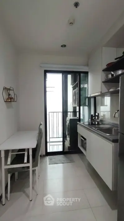 Modern kitchen with dining area and balcony access in a stylish apartment.
