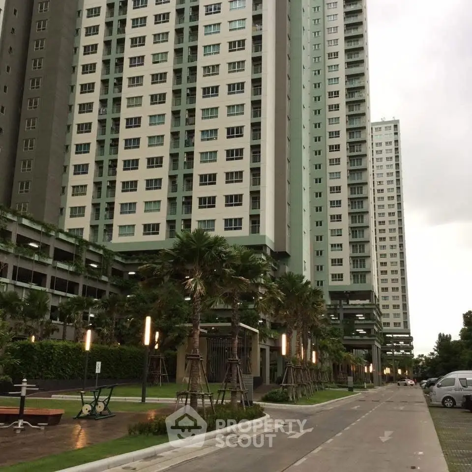 Modern high-rise residential building with lush landscaping and pathway