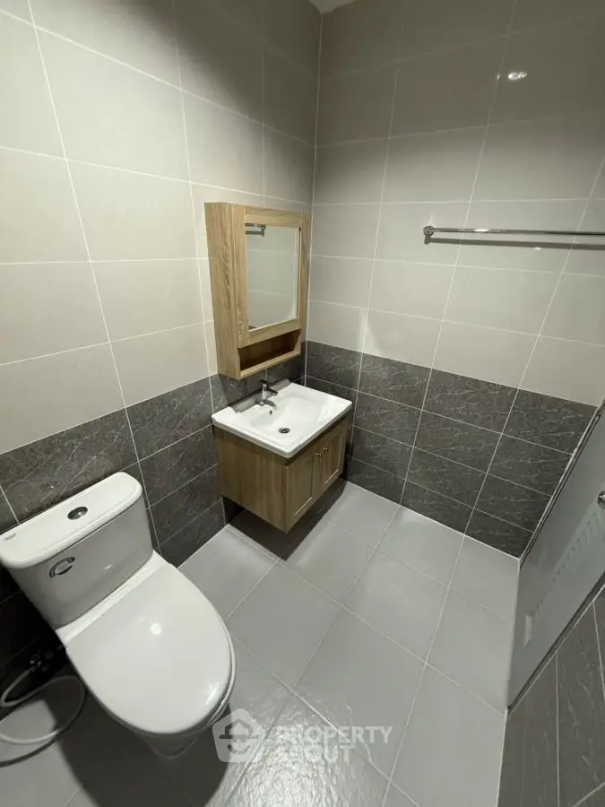 Modern bathroom with sleek tiles and compact vanity unit.