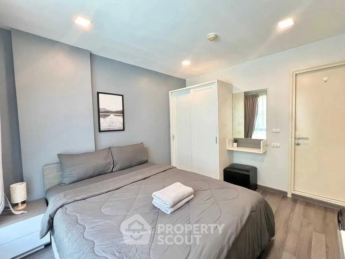Modern bedroom with cozy gray bedding and stylish decor in a contemporary apartment.