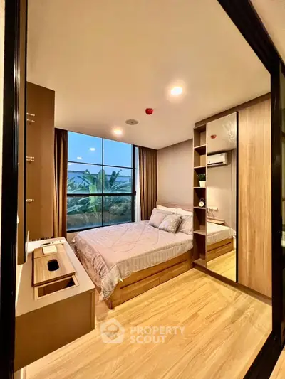 Modern bedroom with large window and wooden flooring, featuring built-in storage and stylish decor.