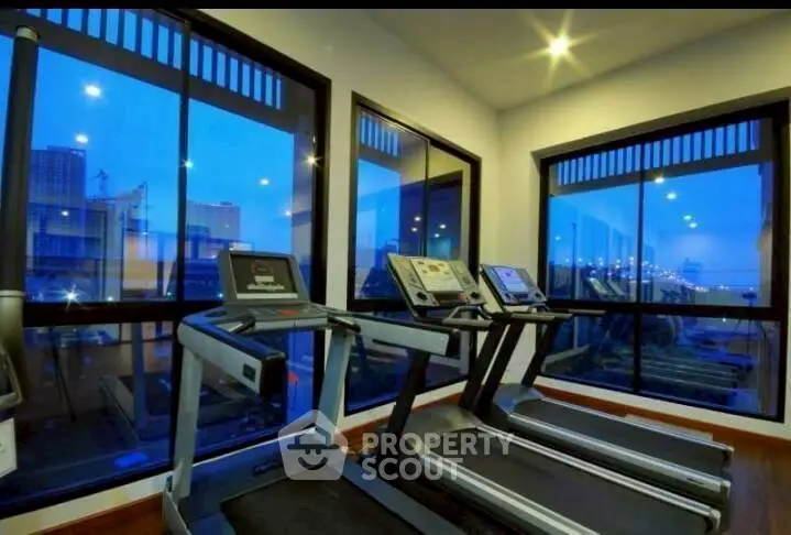 Modern gym with city view and state-of-the-art equipment in luxury residential building.